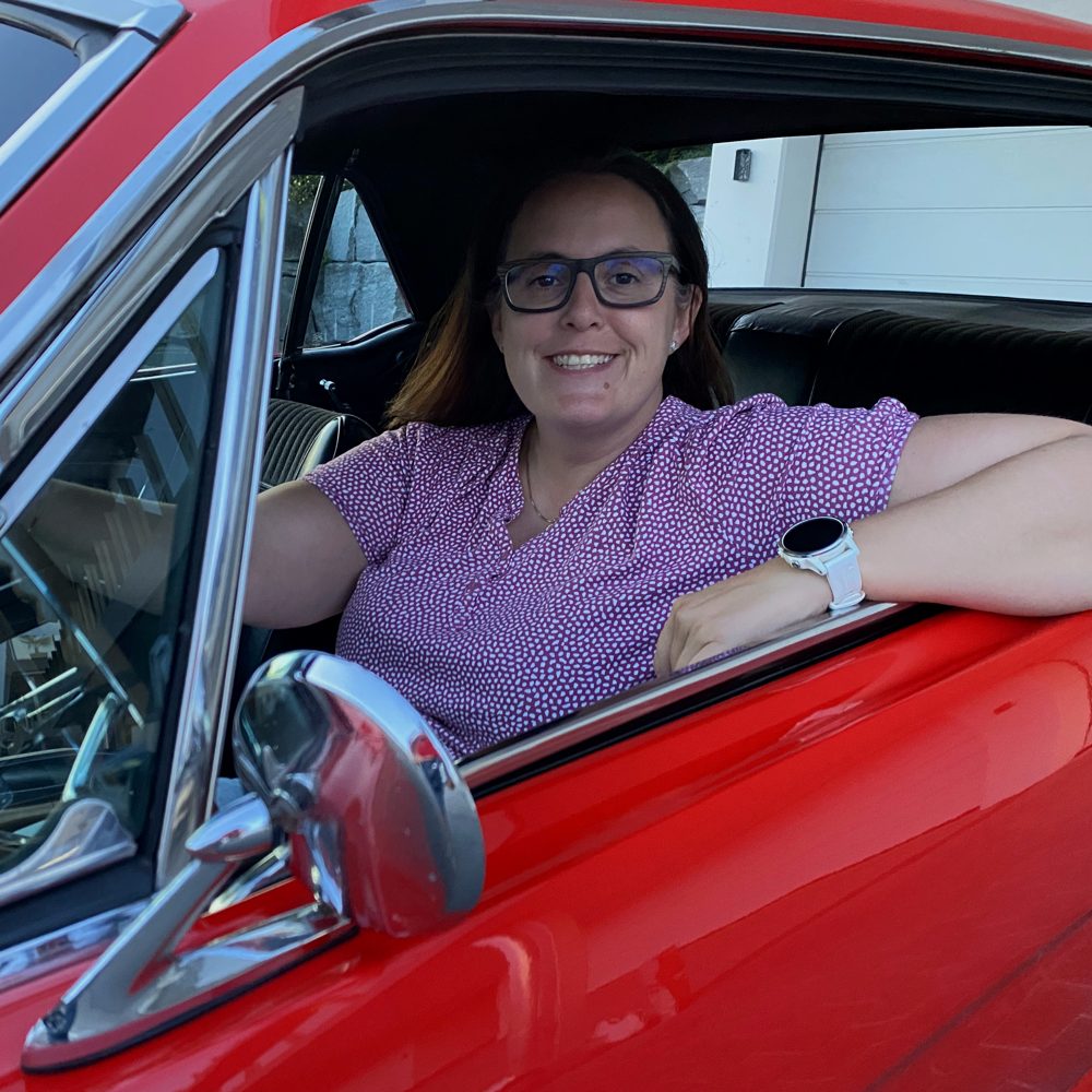Sandra Brack am Steuer eines roten Ford Mustang Oldtimers